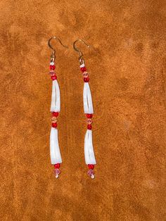 pair of white and red beaded earrings on brown background