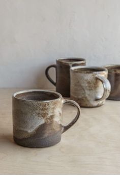 three coffee mugs sitting on top of a wooden table