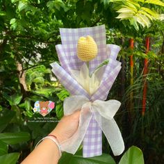 a hand holding up a crocheted flower in the shape of a bow with two flowers attached to it