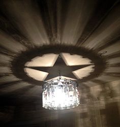 a chandelier hanging from the ceiling in a dark room with light shining on it