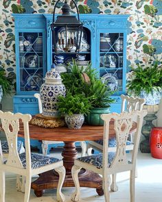 a dining room table with blue china cabinet and chairs