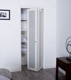 a bedroom with a bed and a white cabinet in it's corner next to a wooden table