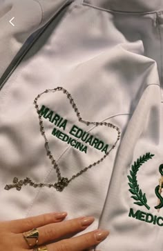 a close up of a person's hand on a white jacket with green lettering