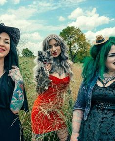 three women dressed up in costumes and makeup posing for the camera with one holding a small dog