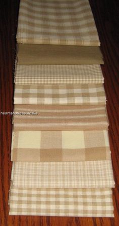 three pieces of plaid fabric sitting on top of a wooden table next to each other