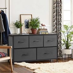 a room with a dresser, chair and potted plants