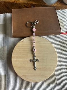 a cross keychain sitting on top of a wooden table next to a purse