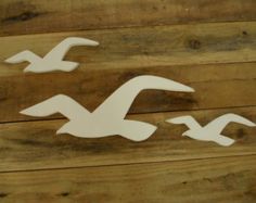 three white birds flying over a wooden floor