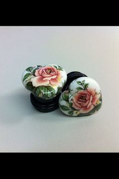 three knobs with flowers painted on them sitting next to each other in front of a white background