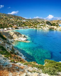 the blue water is surrounded by rocky hills and greenery on either side of it