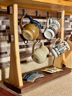 a wooden shelf with cups and mugs hanging from it's hooks on the wall