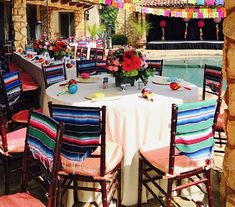 an outdoor dining area with tables and chairs set up for a party by the pool