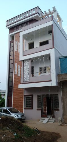 a car parked in front of a multi - story building with balconies on the second floor