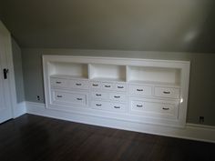 an empty room with white cabinets and wood floors