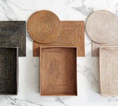 four woven trays sitting on top of a marble counter