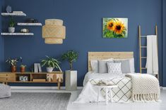 a bedroom with blue walls and white flooring has a sunflower painting on the wall