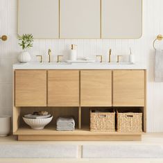 a bathroom with two sinks, mirrors and baskets on the counter top in front of it