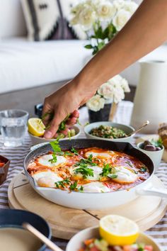 a person is cooking food in a skillet on a table with plates and bowls