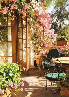 an outdoor table and chairs in front of some flowers