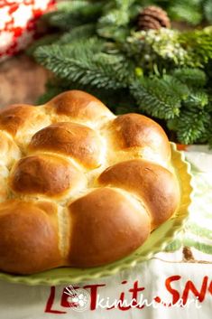 a loaf of bread sitting on top of a green plate next to christmas greenery