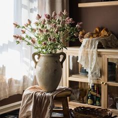 a vase filled with flowers sitting on top of a wooden table next to a window