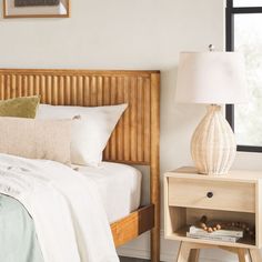 a bedroom with a bed, night stand and lamp on the side table next to it