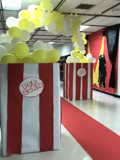 popcorn bags with yellow and white balloons are on the floor in front of red and white striped walls