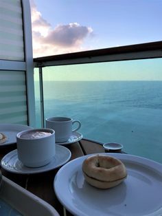 two plates with donuts on them are sitting next to each other near the ocean