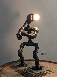 a lamp that is sitting on top of a barrel with a light in the shape of a robot