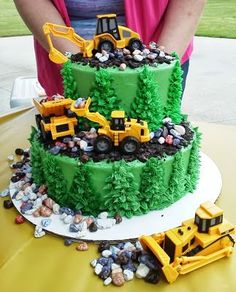 there is a green cake with construction trucks on it