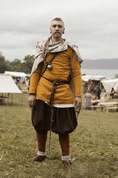 a man dressed in period clothing standing on the grass