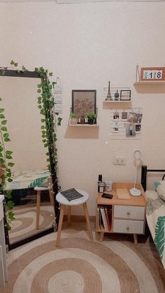 a bedroom with a bed, desk and mirror in it's corner next to a plant on the wall