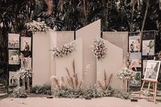 an outdoor ceremony setup with flowers and pictures on the wall, surrounded by palm trees