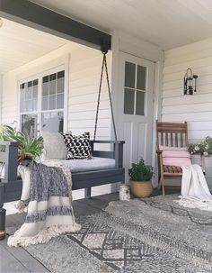 a porch swing sitting on top of a wooden floor next to a white door and window