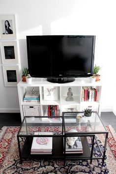 a living room with a television, bookshelf and rug in front of it