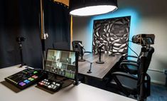 a desk with a camera and some lights on it in front of a large screen