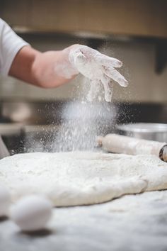 a person is sprinkling flour on top of dough