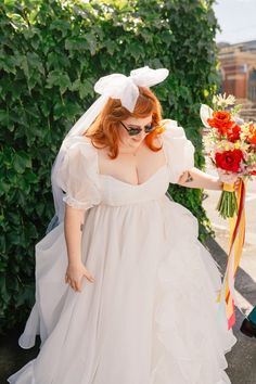 a woman in a white dress is walking down the street with a bouquet on her head