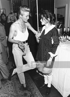 black and white photograph of two women dancing at a party with wine bottles on the table