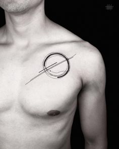 a man's chest with a circle and arrow tattoo on the left side of his chest