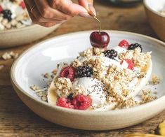 a bowl filled with granola and fruit on top of a wooden table