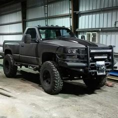 a large black truck parked inside of a garage next to a metal pipe and building