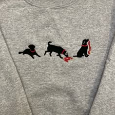 two black dogs with red collars are on a gray sweatshirt that has the same dog design on it