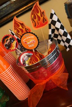 an assortment of cupcakes and candy sticks in a tin can on a table