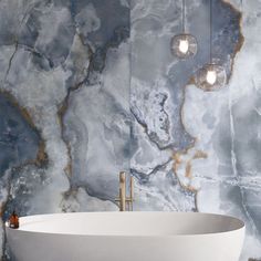 a white bath tub sitting next to a wall with two lights hanging from it's sides