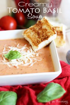 creamy tomato basil soup in a white bowl with toasted bread and cheese on top