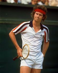 a man holding a tennis racquet on top of a tennis court with people in the background