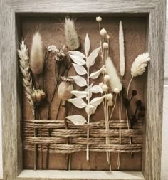 a shadow box with dried flowers in it