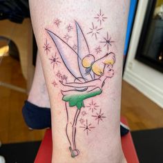 a woman's leg with a tattoo on it that has a tinkerbell holding a knife