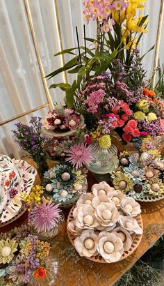 a table topped with lots of different types of flowers and plates on top of it